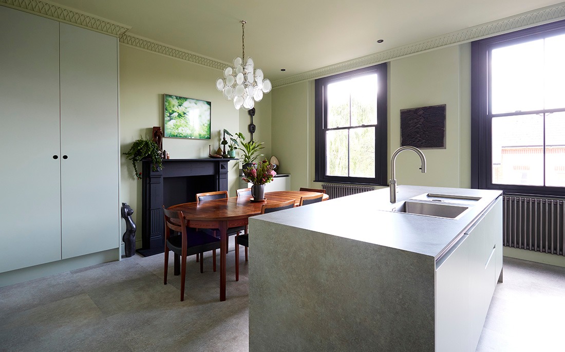 Kitchen island and dining table beneath a white pendant light, with Victorian sash windows
