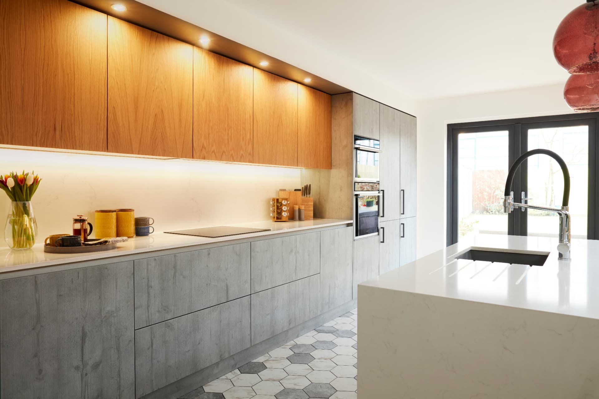 Concrete-effect handleless kitchen units with walnut upper cabinets and marble-veined worktop