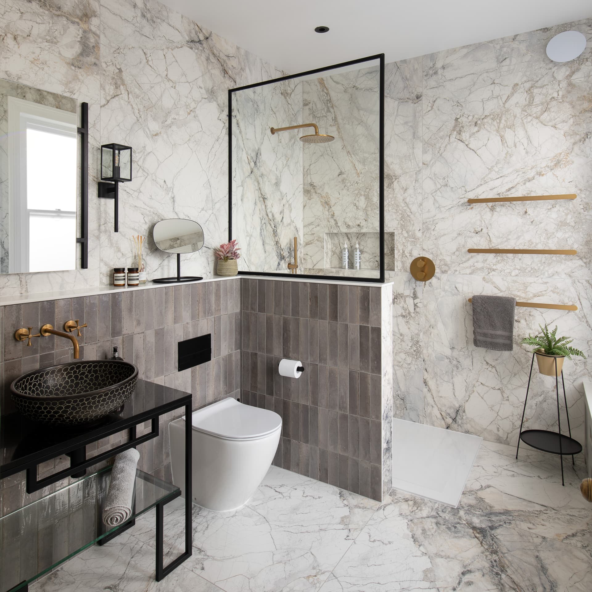 Crystal Palace bathroom after renovation, with marble-effect walls, a black-framed walk-in shower, brushed brass fittings and a vanity basin