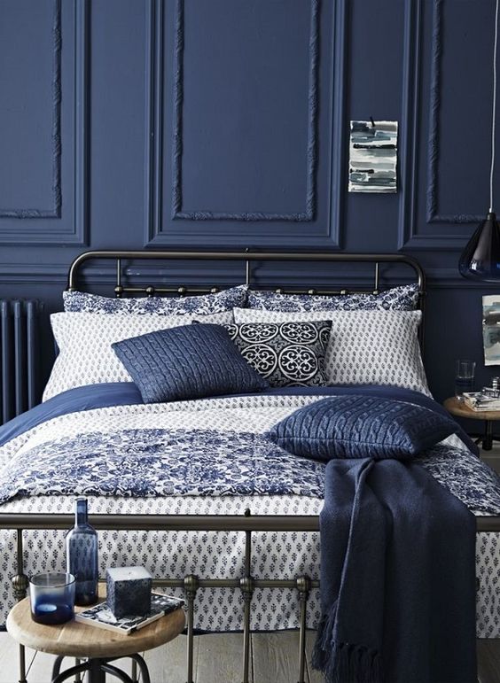 Navy panelled bedroom with an iron bed frame and blue and white bedding