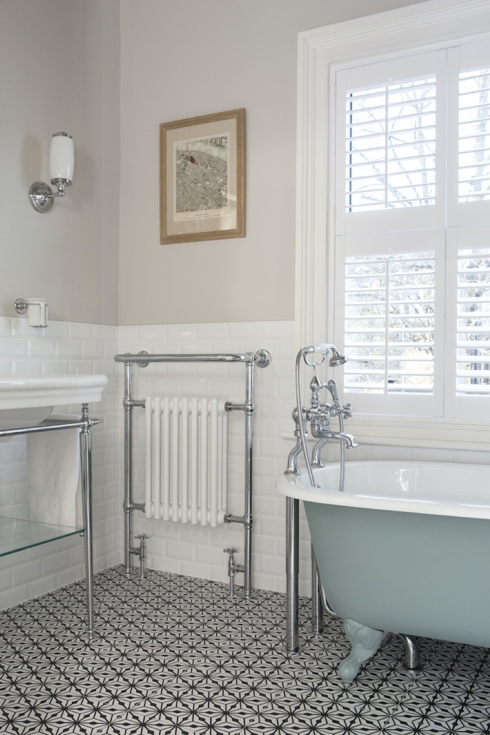 Roll-top bath with traditional heated towel rail and framed print