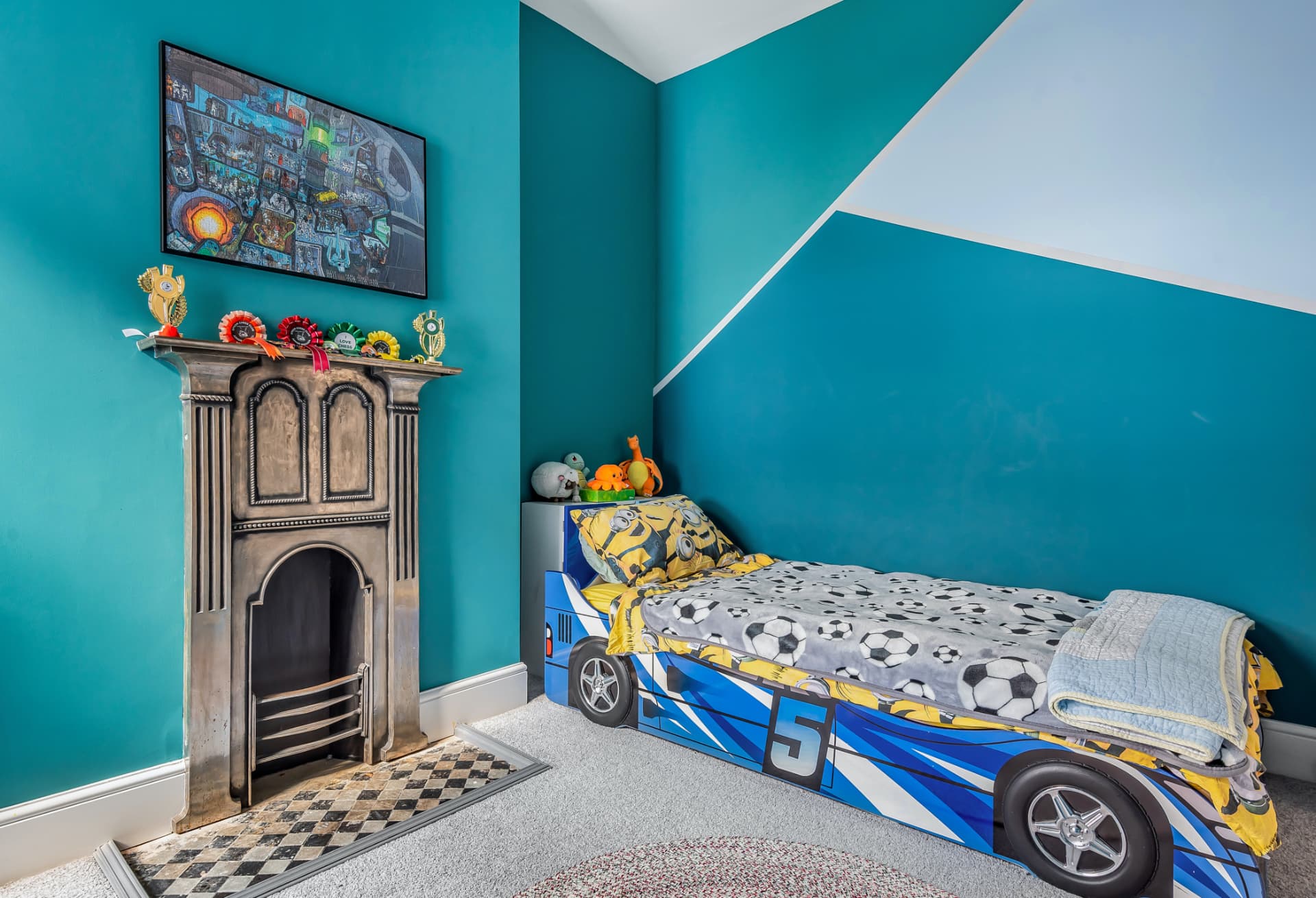 Child's bedroom in teal with racing car bed and cast-iron fireplace