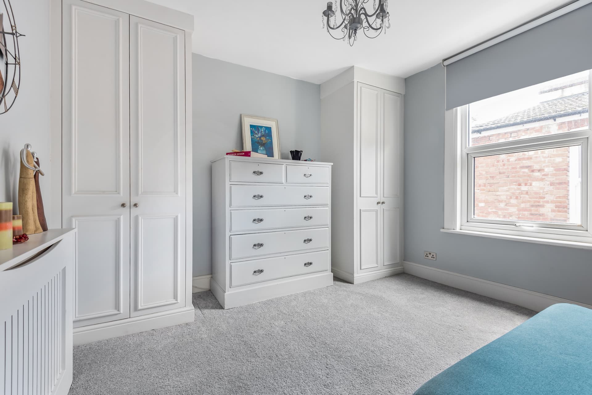 Bedroom with white fitted wardrobes, chest of drawers and grey carpet