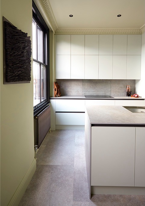 Pale handleless kitchen with stone-topped island and sash window
