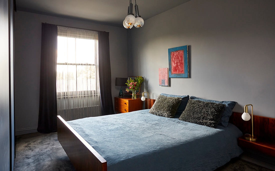 Main bedroom with blue bedding, sash window and bespoke wall-mounted headboard