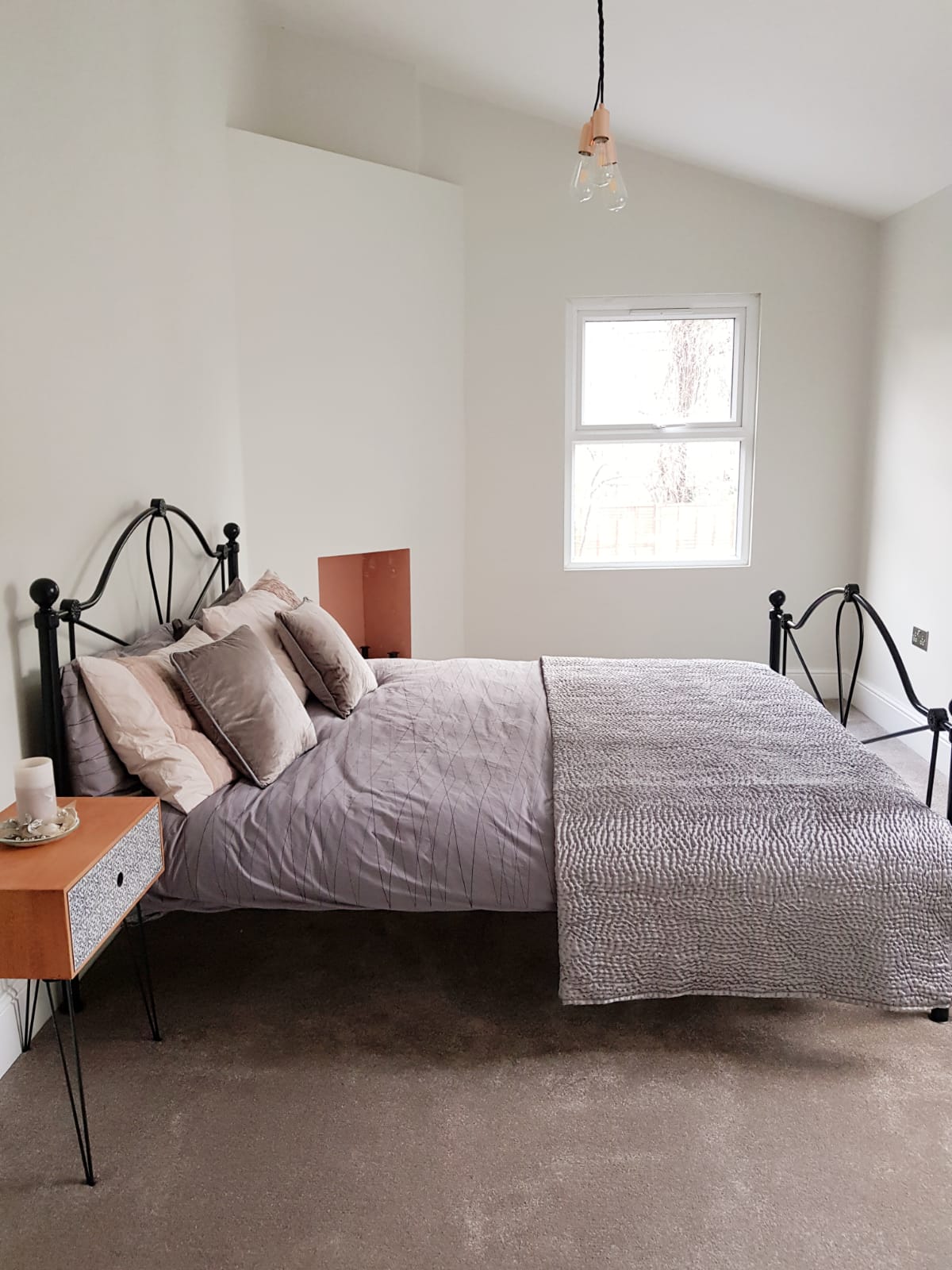 Vaulted master bedroom with exposed pitched ceiling, iron bed and blush bedding