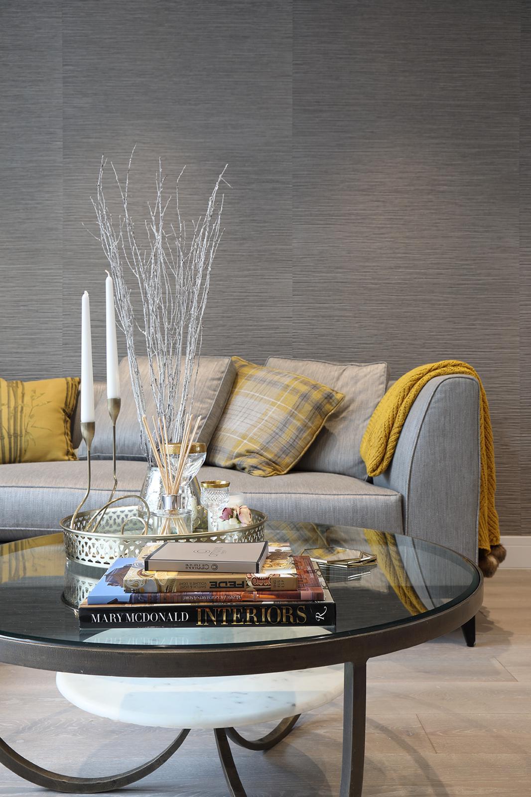 Living room in Clapham with grey sofa, mustard throw and glass coffee table against grasscloth wallpaper