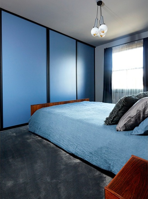 Main bedroom with floor-to-ceiling blue wardrobes, blue bedding and vintage pendant
