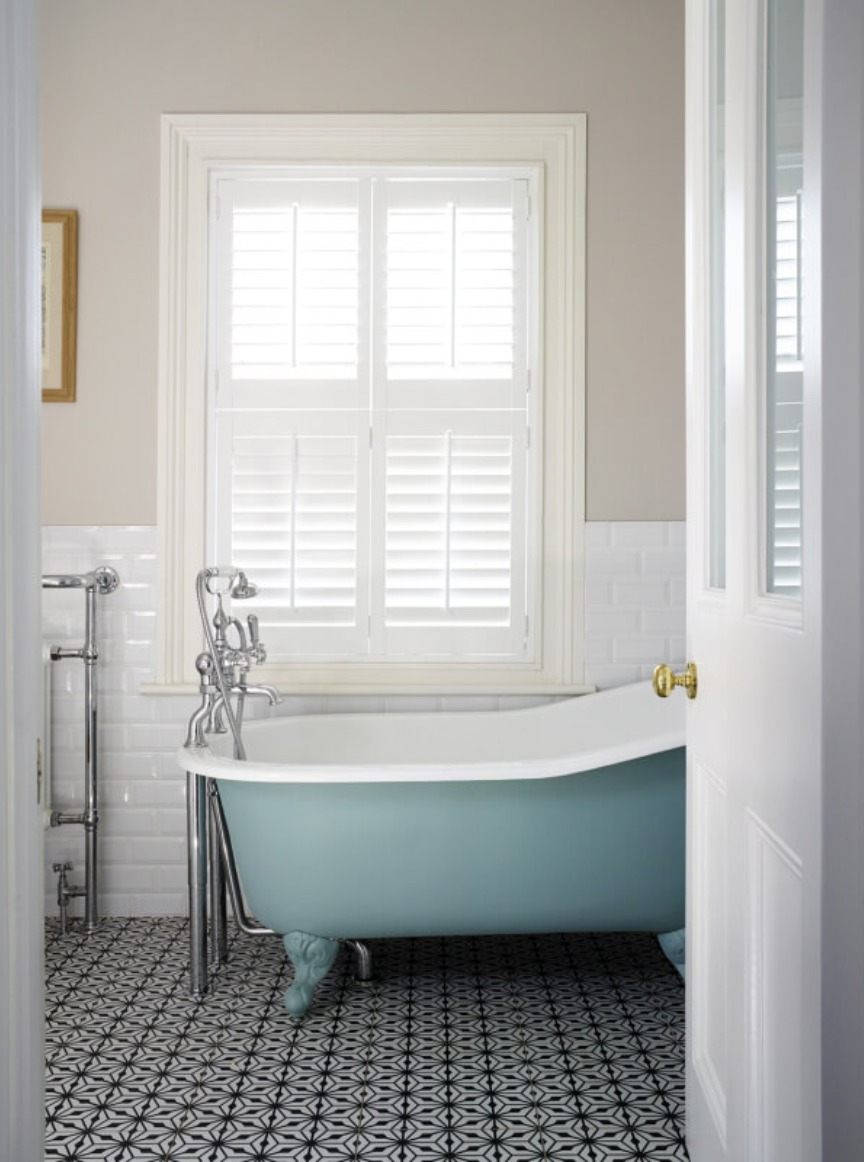 Bathroom with blue roll top bath and patterned floor tiles