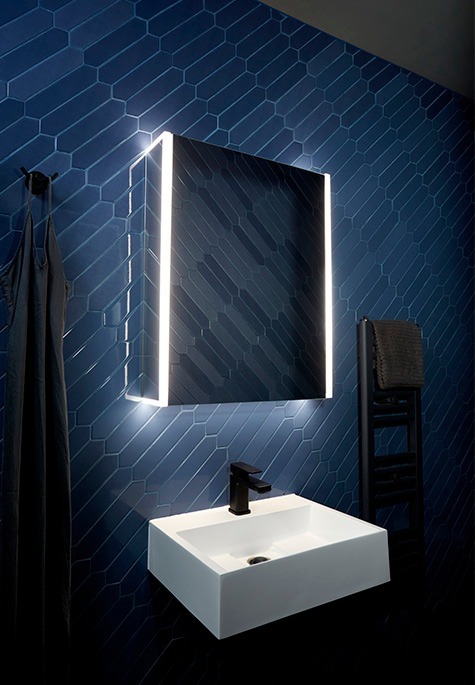 Cloakroom with dark blue herringbone wall tiles, backlit mirror and white basin