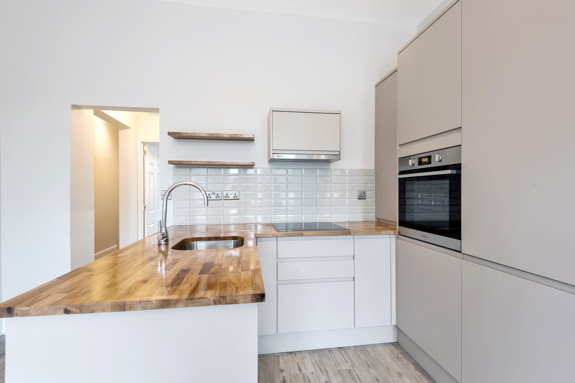 Grey handleless kitchen with oak worktop, white metro tiles and open shelves