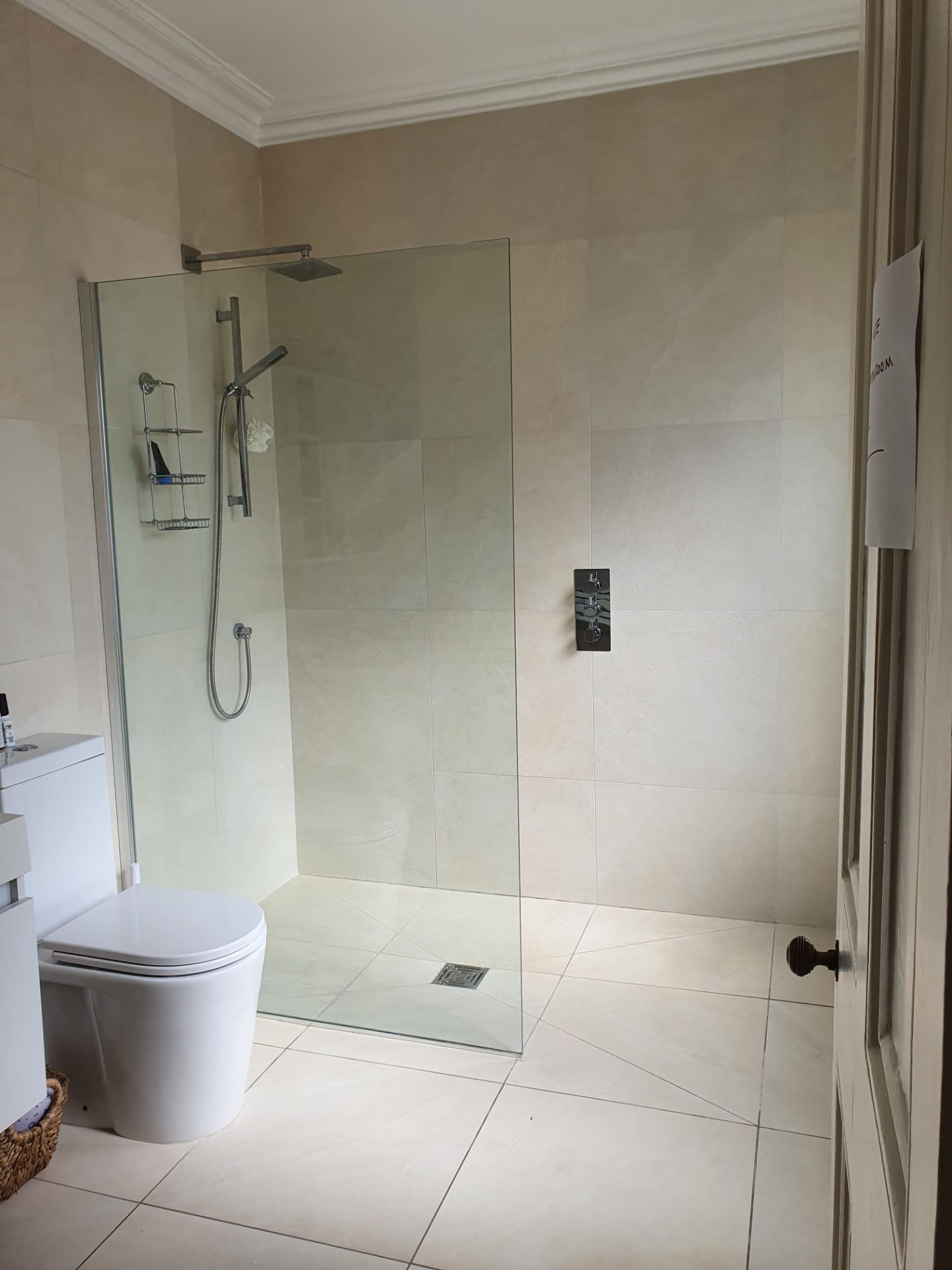 Crystal Palace bathroom before renovation, with an enclosed shower cubicle, beige wall tiles and chrome fittings