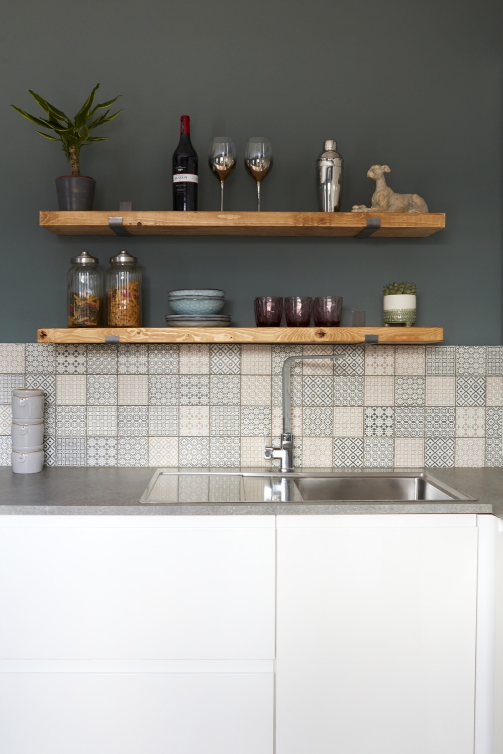 Open timber shelves above a stainless steel sink with patterned splashback tiles