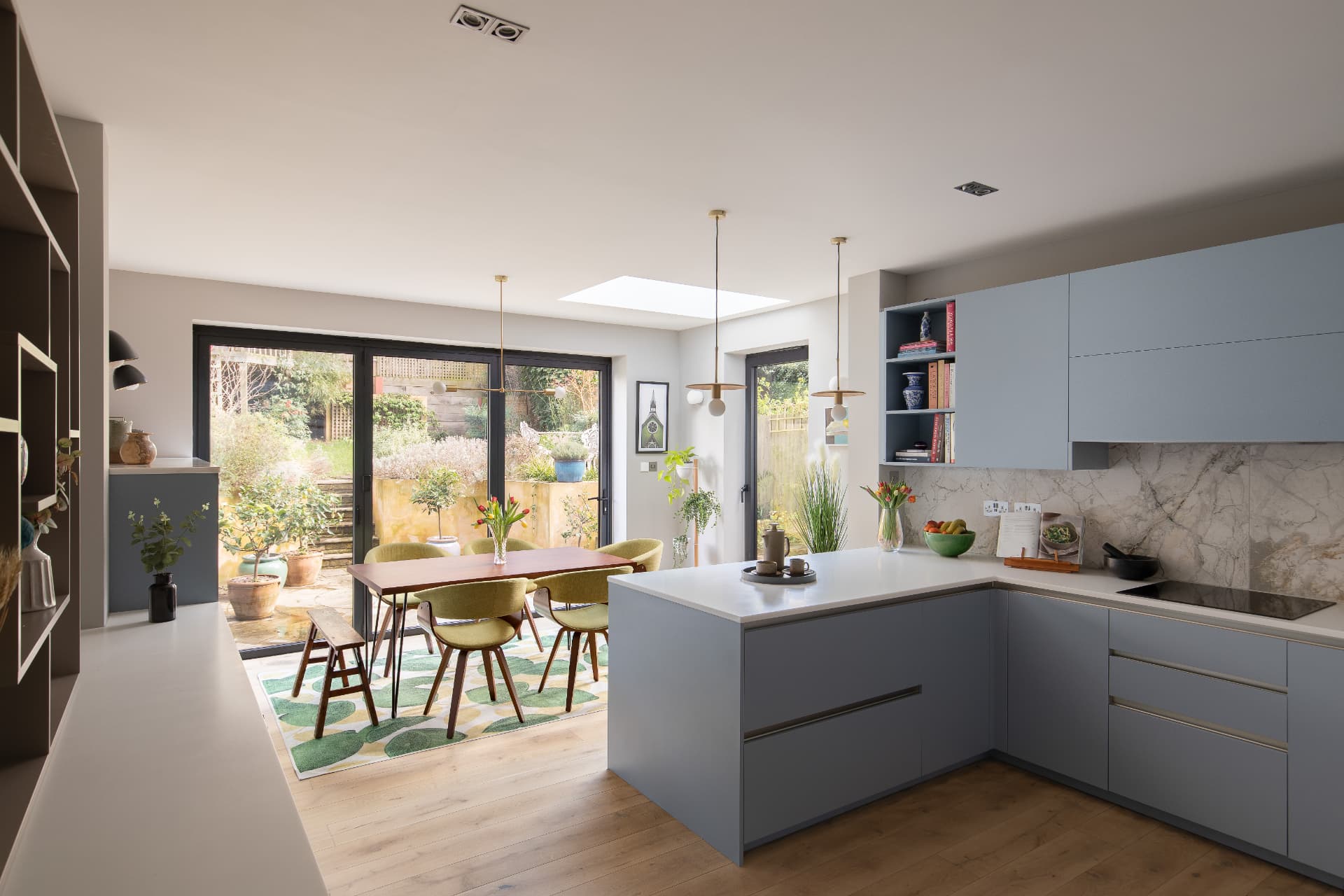 Open-plan kitchen diner with pale blue handleless kitchen, peninsula and garden doors in a Crystal Palace Victorian house