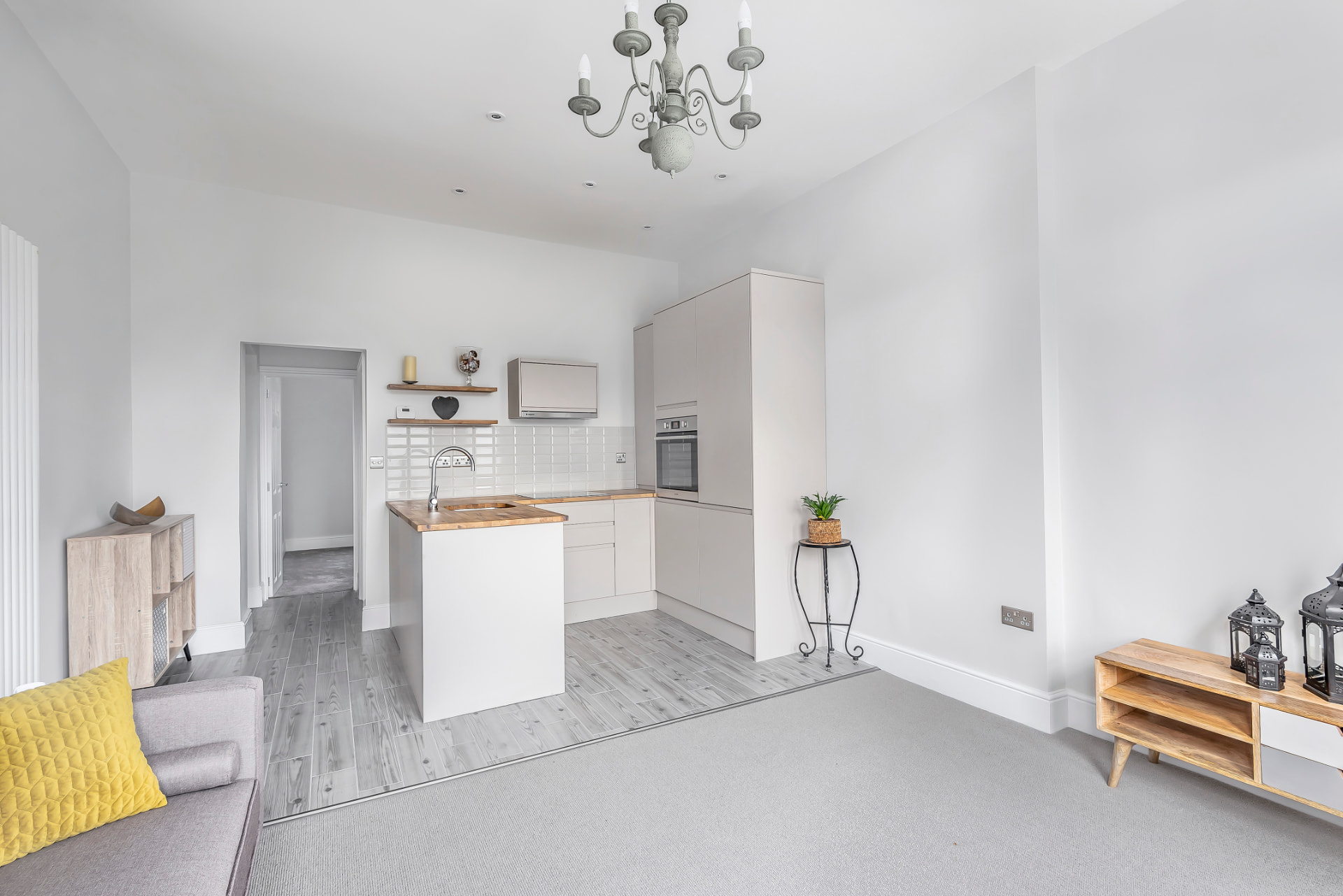 Open-plan living space with grey kitchen units, white island and light grey flooring