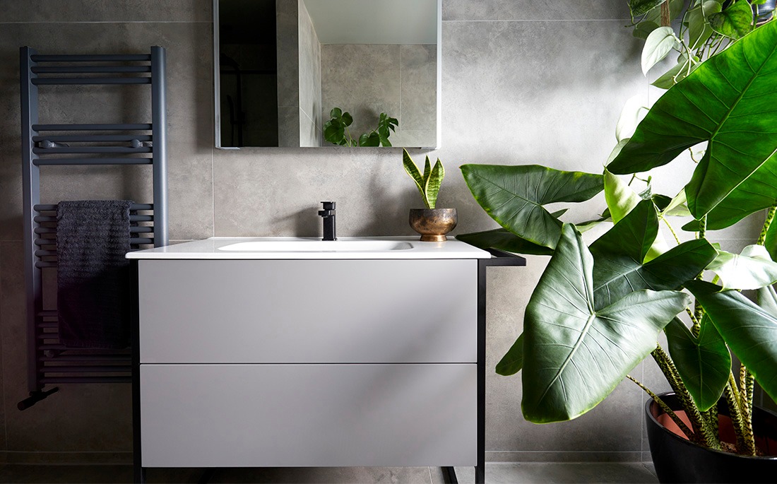 Bathroom vanity unit with white basin, black heated towel rail and plants