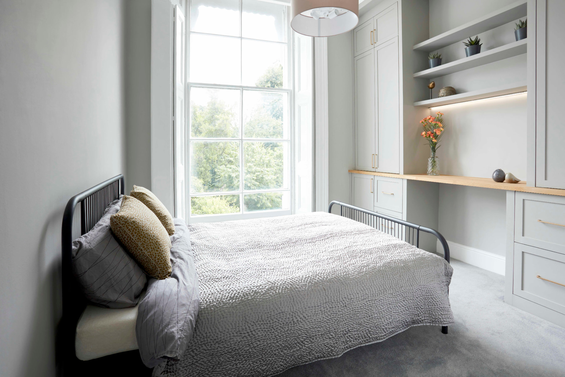 Bedroom in a Belsize Park flat with tall sash window, fitted wardrobes and built-in desk with shelves