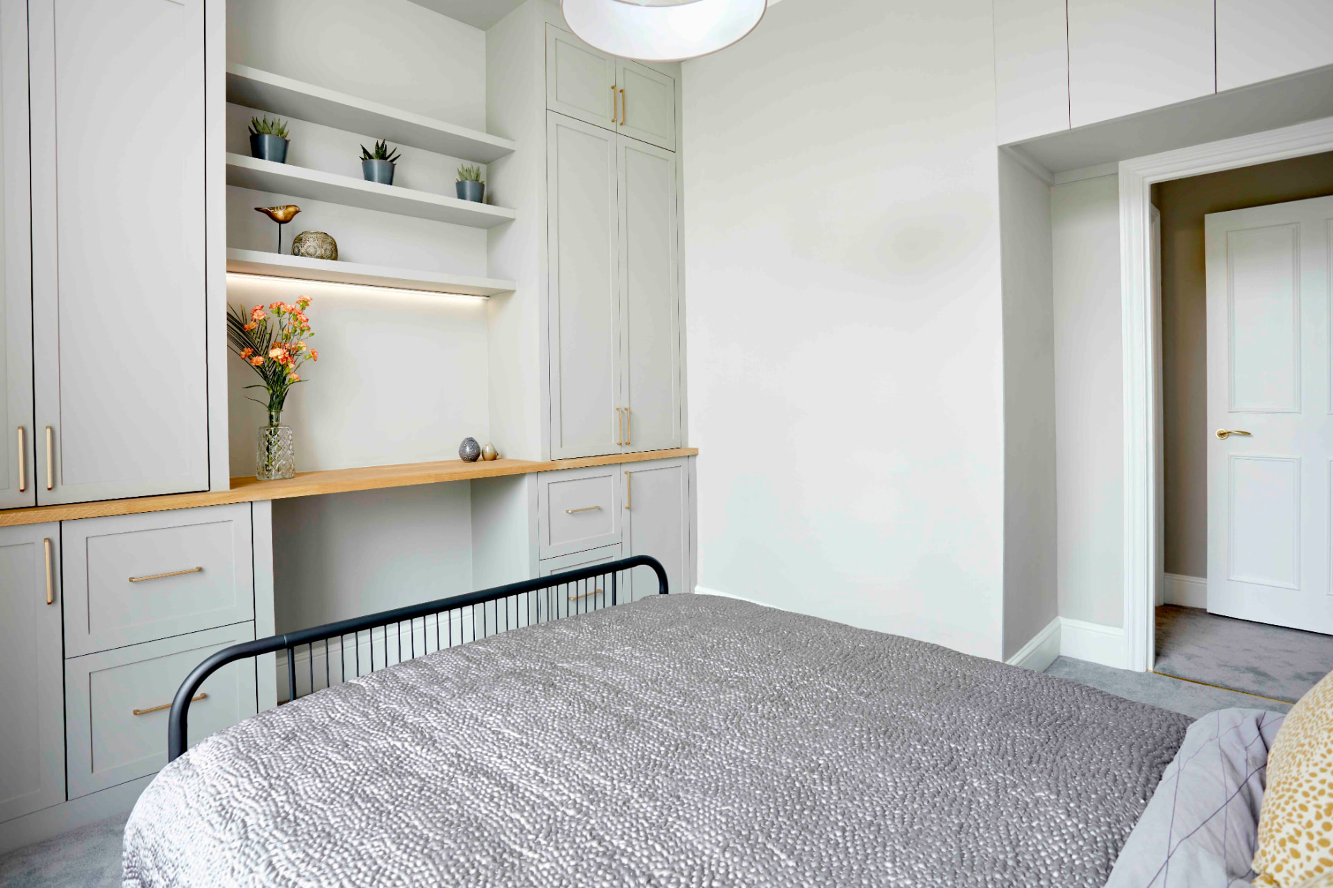Fitted shaker wardrobes and oak desk around the bed, with open shelving