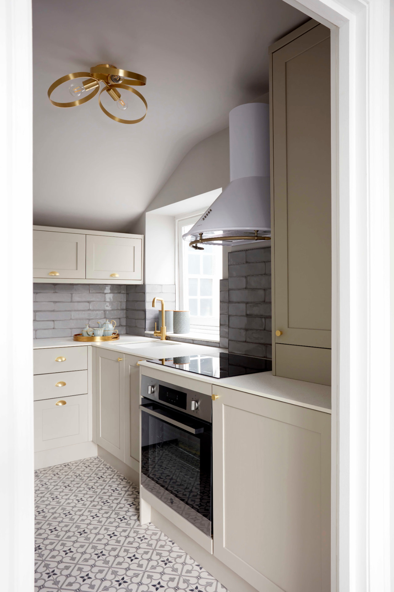 Compact galley kitchen with shaker cabinets, brass handles and patterned floor tiles