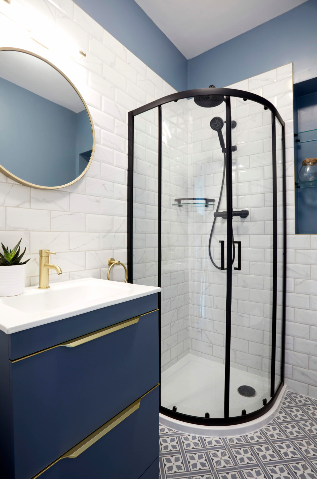 Shower room with navy vanity, brass handles, round mirror and black quadrant shower